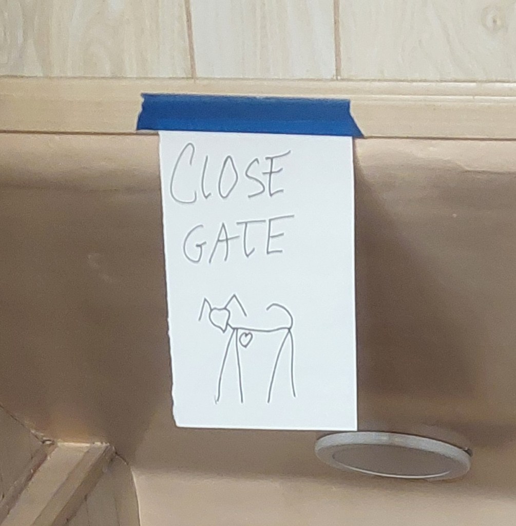 A hand-drawn sign attached to a wall that reads 'CLOSE GATE' with a simple sketch of a dog below it.